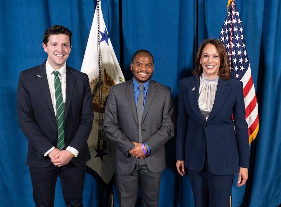 Kamala Harris, Isaiah Bolden, Ike Irby in front of flags