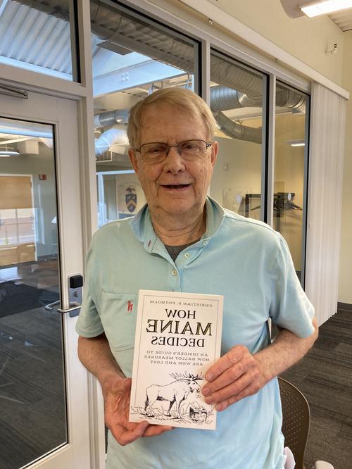 prof chris potholm holding copy of latest book 'how maine decides'